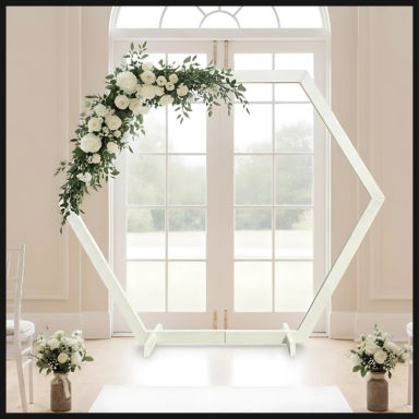A hexagonal wedding arch adorned with white flowers and greenery, set in a bright venue.