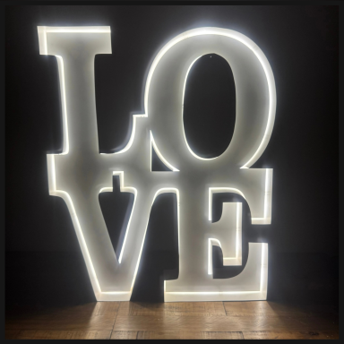 Illuminated "LOVE" sign with backlighting against a dark background.