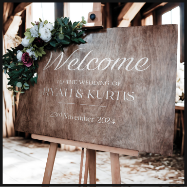 Wooden welcome sign adorned with flowers, for the wedding of Yan and Kurtis, September 2024.