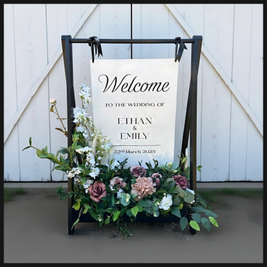 Welcome sign for a wedding, adorned with floral arrangements.