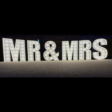 Illuminated letters spelling "MR & MRS" in a festive setting.