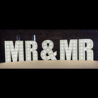 Illuminated letters spelling "MR & MR" on a dark background.