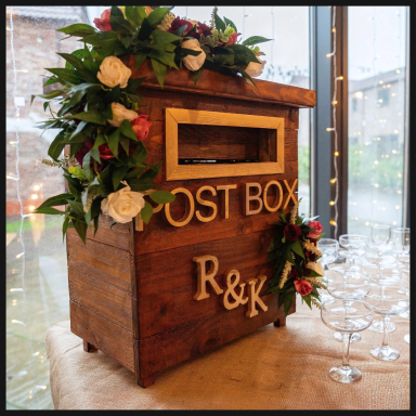 Wooden post box with floral decorations, featuring the letters R & K.