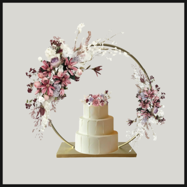 Three-tiered wedding cake surrounded by a floral hoop decoration.