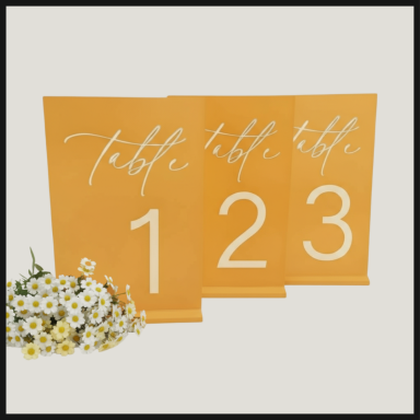 Three orange table numbers (1, 2, 3) with white lettering, accompanied by white flowers.