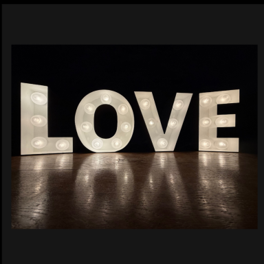 Bright, illuminated letters spelling "LOVE" against a dark background.